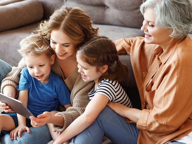 mother, adult daughter and grandchildren read together in one home