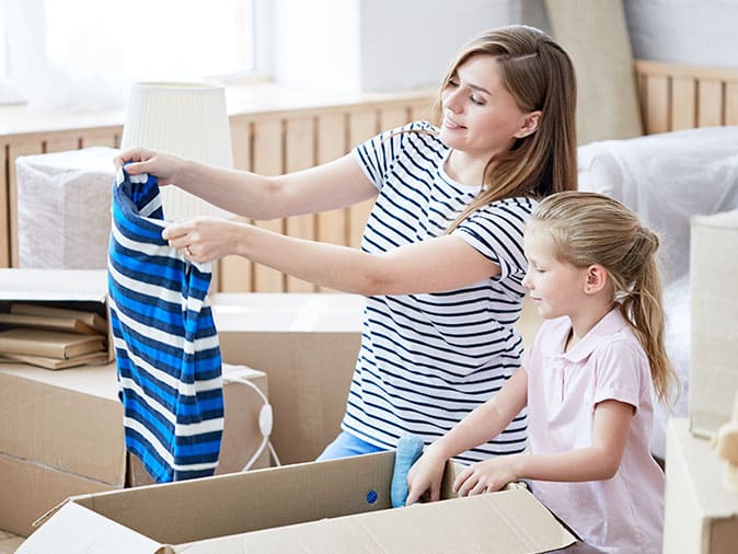 mother and daughter packing clothes up for a move